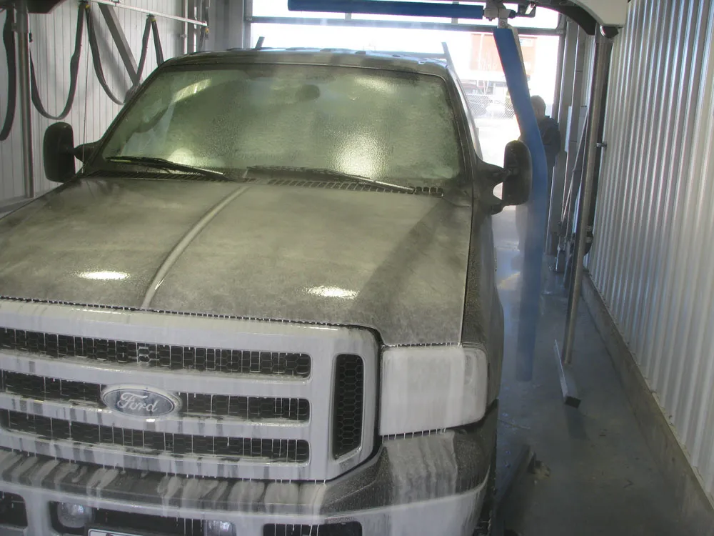 Pickup truck covered in pre-soak in a wand wash bay at Arctic Autowash, Edmonton